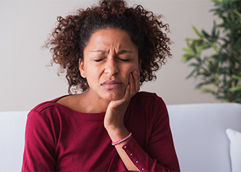 Woman with toothache sitting on couch at home.