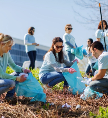 Group of people picking up trash in field